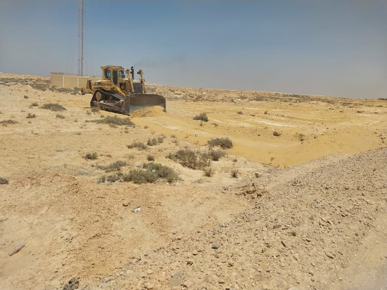 بلدوزر يزيل الأتربة في أرض صحراوية