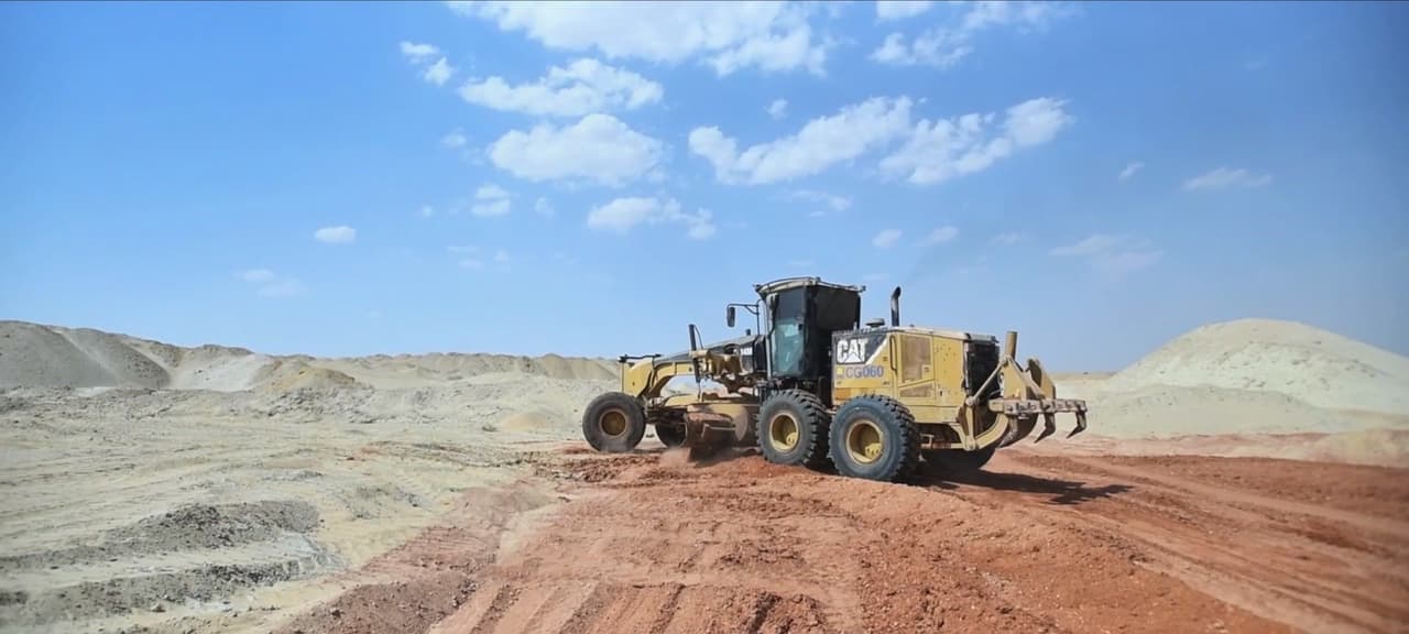 A motor grader levelling a road on a work site